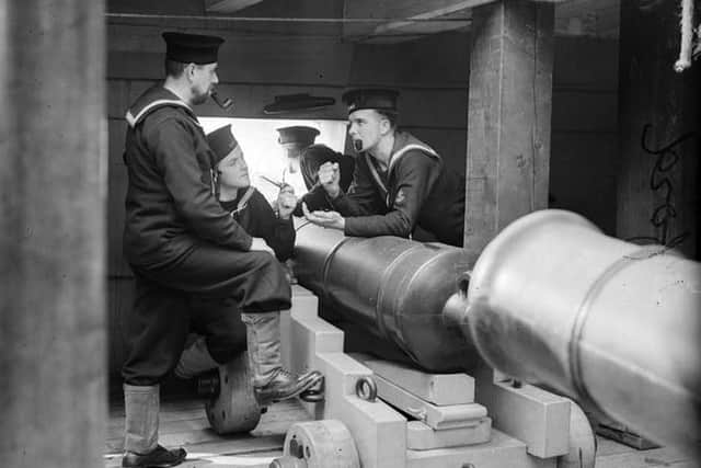 Gathered around HMS Victorys cannon during stand easy we see four wartime sailors.