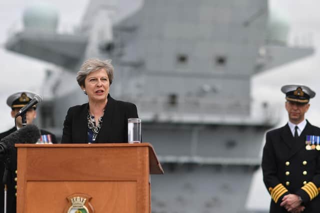 Commodore Jerry Kyd (R), listens as Britain's Prime Minister Theresa May stands on the flight deck and speaks to crew members of HMS Queen Elizabeth after she arrived in Portsmouth for first time. Picture: BEN STANSALL/AFP/Getty Images