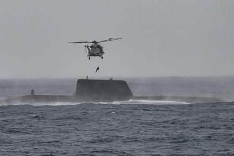 A Merline helicopter winches a submariner from HMS Astute before taking them to HMS St Albans. Photo: Royal Navy