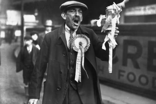 Portsmouth supporter wearing a rosette and holding a model FA Cup arrives in London for the FA Cup final against Bolton Wanderers at Wembley in 1929.