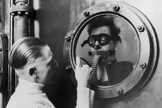 Circa 1939:  An instructor signals through a porthole to a seaman at the bottom of a 15 foot tank, during submarine crew training at the DSEA Instructional Centre at Portsmouth.  (Photo by Keystone/Getty Images)