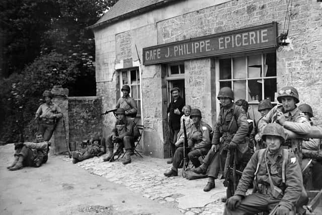 Picture released: June 20, 1944. BRIEF 'TIME OUT' ON THE INVASION FRONT - Exhausted from their rapid advance inland from the Normandy beachhead, U.S. soldiers relax for a few minutes outside a French cafe.