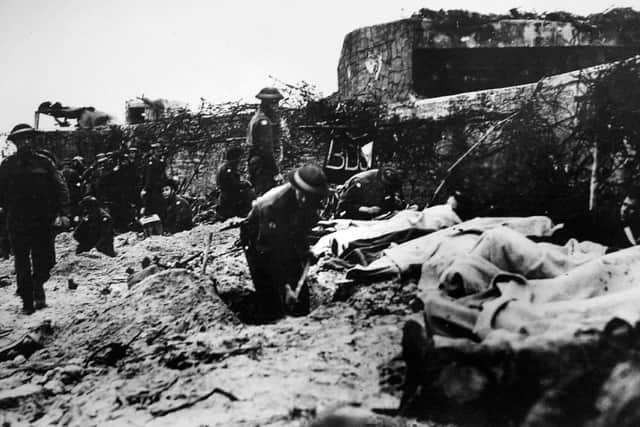 Photograph of beach defences and troops.