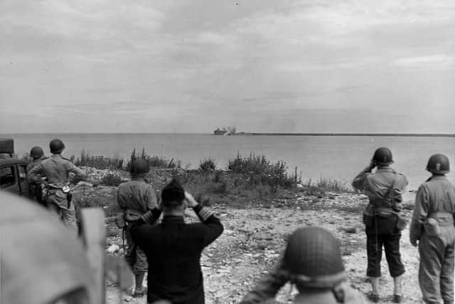 4 June 1944. Standing on a promontory in plain view of Nazi batteries, U.S. Army and Navy officers watch Allied planes deliver a thunderous bombardment against enemy forts guarding Cherbourg harbour.  When picture was taken, the background was one of the two remaining bastions held by the Nazis on the approaches to the harbour.