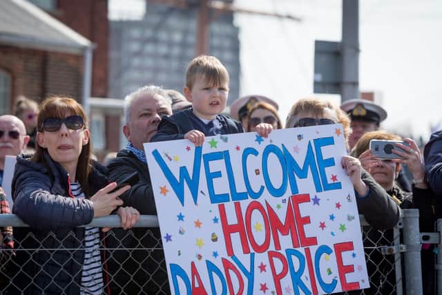 A child holds a welcome sign for his dad