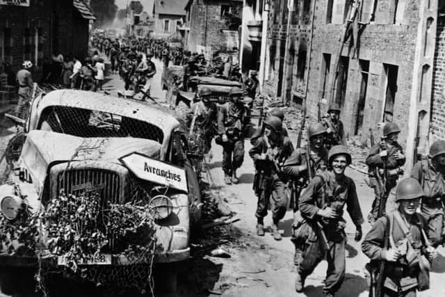 Infantry Advances 9th August 1944:  US infantrymen make their way past a wrecked German truck on the way to Avranches during the Allied invasion of Normandy.  (Photo by Keystone/Getty Images)