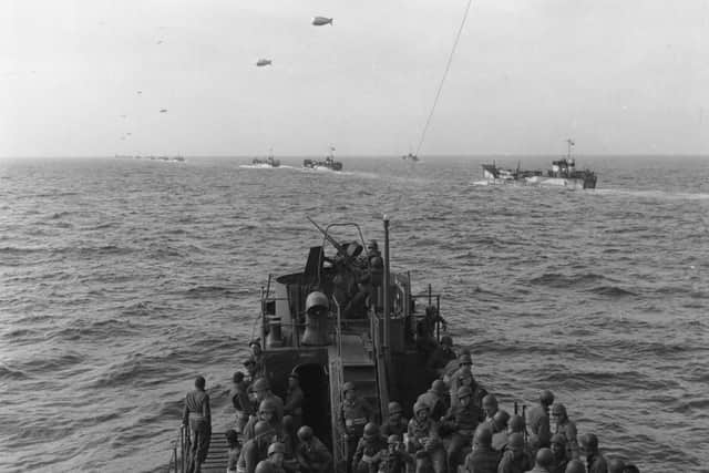 Convoy To Normandy June 1944:  Members of the 9th Air Force watch a long line of landing craft carrying barrage balloons, on their way over to Normandy.  (Photo by Keystone/Getty Images)