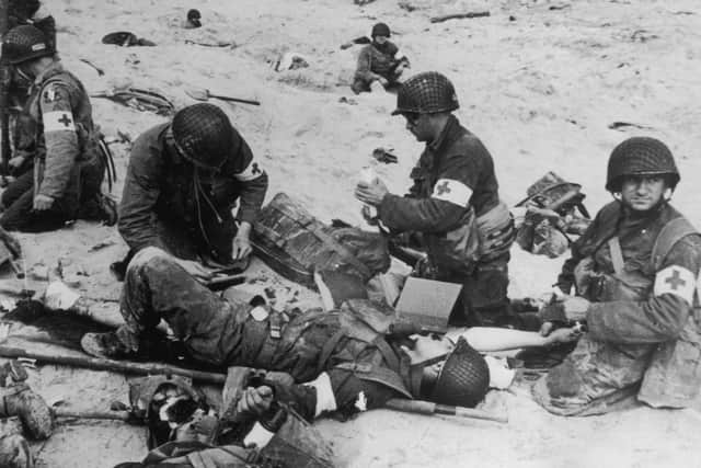 Normandy Landings 6th June 1944:  American medics administer first aid to wounded soldiers on Utah beach in Normandy, France, whilst in the background other troops 'dig-in' in the soft sand.  (Photo by Hulton Archive/Getty Images)