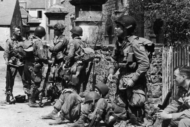 Paratroopers Relax. US paratroopers of the 82nd Airborne Division relaxing after liberating the village of Sainte-Mere-Eglise in Normandy, during World War II, 8th June 1944. The shoulder patch of the nearest standing soldier has been erased, presumably by the censors. (Photo by Keystone/Getty Images)