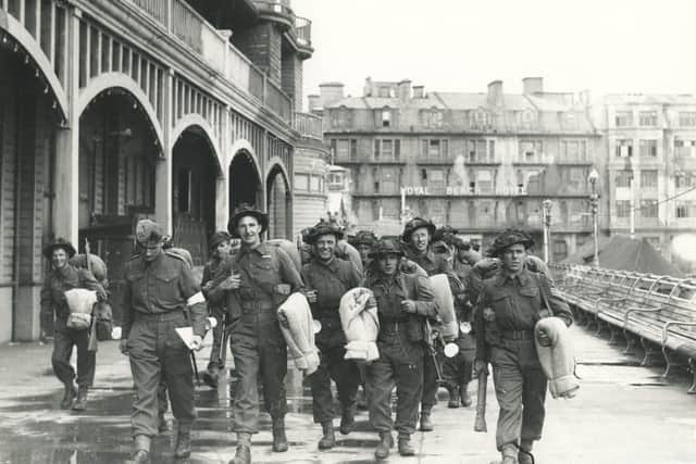 Some smiling, others in deep thought; soldiers walk along South Parade Pier to embark for Normandy.