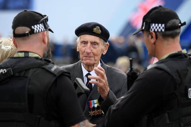 Former British Royal Marine, and D-Day veteran Jim Booth (C), talk with armed members of Britain's police.