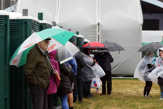 People shelter from the wind and rain behind the loos.       
Picture: Chris Moorhouse