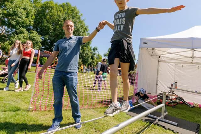 Brooke Jeune (8yrs) practices tight rope walking at the Top Banana Circus Skills stall, assisted by her father Lee Jeune. Picture: Duncan Shepherd