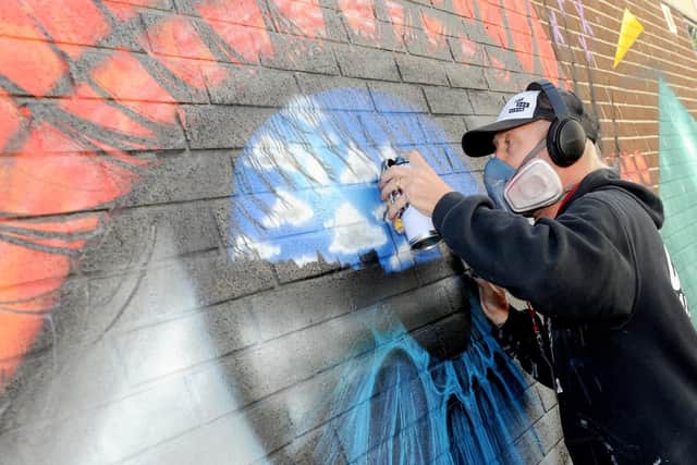 Artist, My Dog Sighs, puts the finishing touches to his trademark reflective eye.
Picture: Sarah Standing
