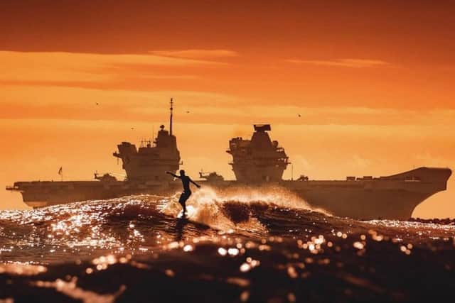HMS Queen Elizabeth has made a huge impact in Florida, with local officials declaring an official day of celebration to honour the aircraft carrier. Her Queen Elizabeth is pictured in Florida with a surfer in the foreground. Photo: Ellen Glasser/Adam King