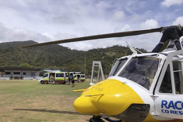 In this photo provided by Royal Automobile Club of Queensland (RACQ) Rescue, a helicopter and ambulances used in the rescue of two tourists attacked by a shark are parked on a sporting ground, near Airlie Beach, Australia. Picture: (RACQ via AP)