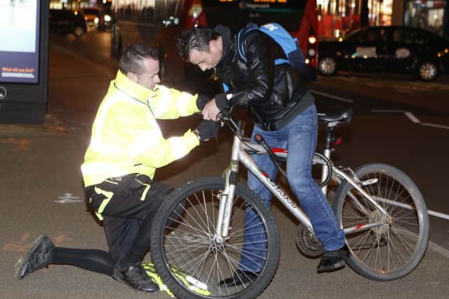 James Luckman putiting a light on Sergio Teixeira's bicycle in London Road, Portsmouth