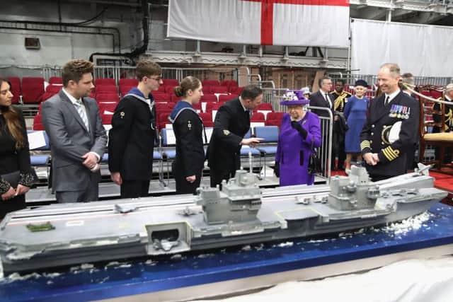 The Queen and the ship's Captain, Commodore Jerry Kyd (right), view a cake modelled on HMS Queen Elizabeth, during the commissioning of HMS Queen Elizabeth Picture: Chris Jackson/PA Wire