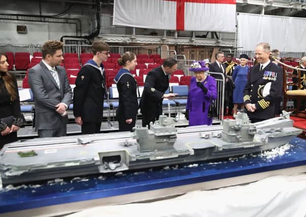 The Queen and the ship's Captain, Commodore Jerry Kyd (right), view a cake modelled on  HMS Queen Elizabeth, during the commissioning of HMS Queen Elizabeth     Picture:  Chris Jackson/PA Wire