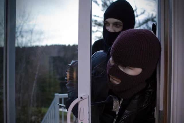 Two burglars entering a house through a patio door Picture posed by models