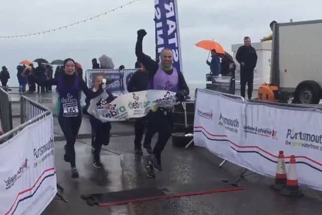 Dave Rodrigues crosses the line of the marathon flanked by Grace and Freddie Fincham