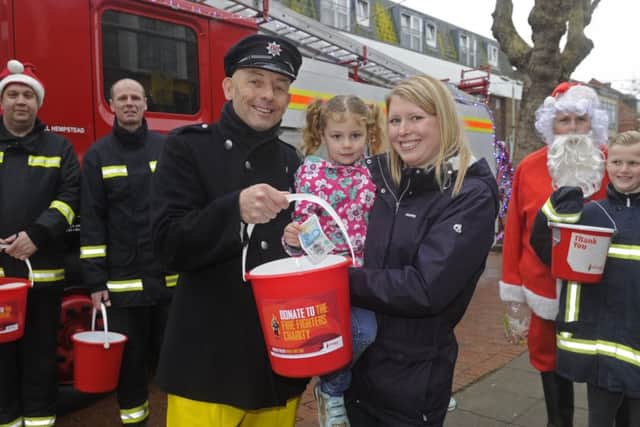 Portchester firefighters are all smiles as they launch their Christmas charity collection in Portchester Precinct. Firefighter Jasper Taylor with Claire Goldstone and her daughter Sophie, 4, from Portchester.Picture Ian Hargreaves  (171686-1)