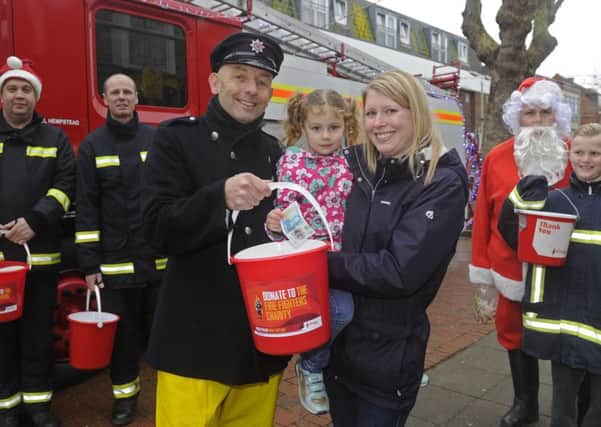 Portchester firefighters are all smiles as they launch their Christmas charity collection in Portchester Precinct. Firefighter Jasper Taylor with Claire Goldstone and her daughter Sophie, 4, from Portchester.
Picture Ian Hargreaves  (171686-1)