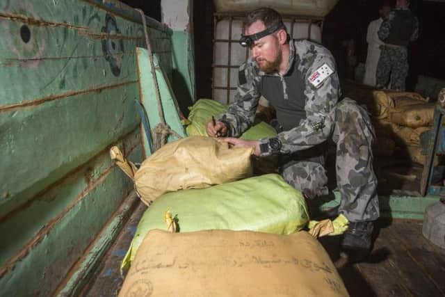 Petty Officer Electronics Technician Leslie Floyd numbers parcels of seized narcotics as HMAS Warramungas boarding team conduct an illicit cargo seizure. 20180102