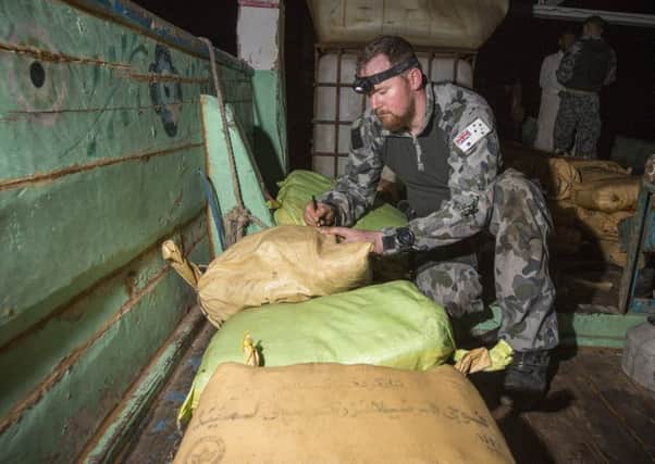 Petty Officer Electronics Technician Leslie Floyd numbers parcels of seized narcotics as HMAS Warramungas boarding team conduct an illicit cargo seizure. 20180102