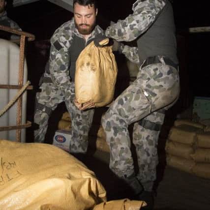 Able Seaman Combat Systems Operator Shamira Altschwager (right) passes a parcel of seized narcotics to Leading Seaman Marine Technician James Phillips as HMAS Warramungas boarding party conduct an illicit cargo seizure during operations in the Middle East. 20180102