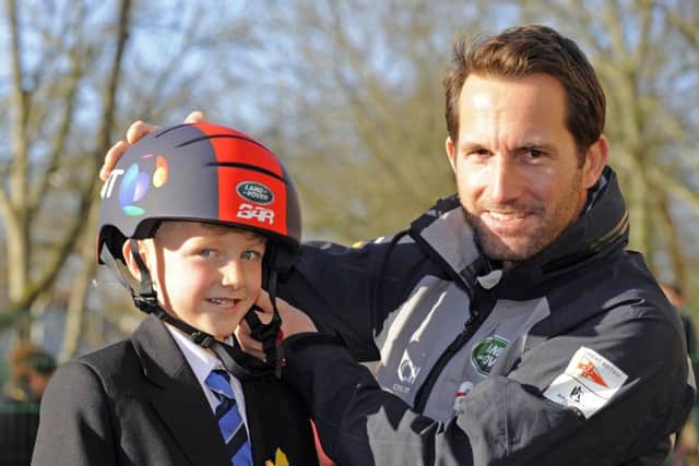 Maxim Turner tries on a helmet assisted by Sir Ben Ainslie
Picture: Malcolm Wells (180122-5419)