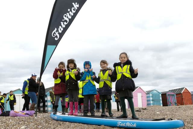 Schoolchildren balance on a paddle board on the beach mikeowensphotography.com
