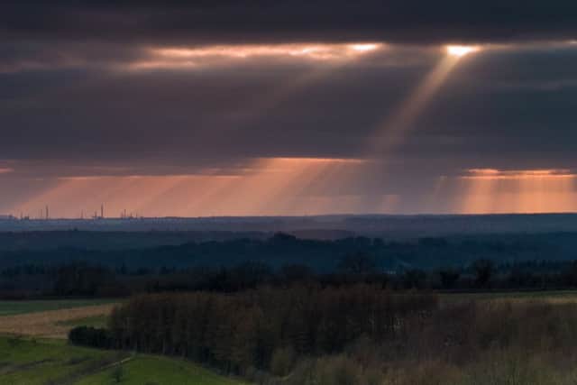 Rays of sun spotlight Fawley from a stormy sky just before sunset