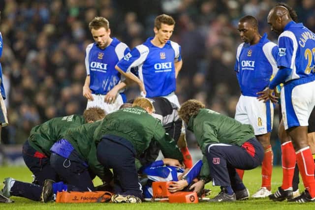 The Pompey players gather round Pedro Mendes as he is placed on a stretcher