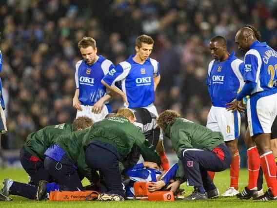 The Pompey players gather round Pedro Mendes as he is placed on a stretcher
