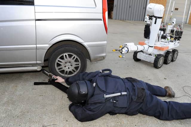 An operator prepares to remove a suspect item from beneath a vehicle