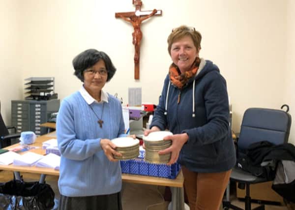 Sister Maura, pastoral assistant at Portsmouth Catholic Cathedral, donating the Bishops Plates to City of Portsmouth Charitable Friends volunteer Tracy McClure