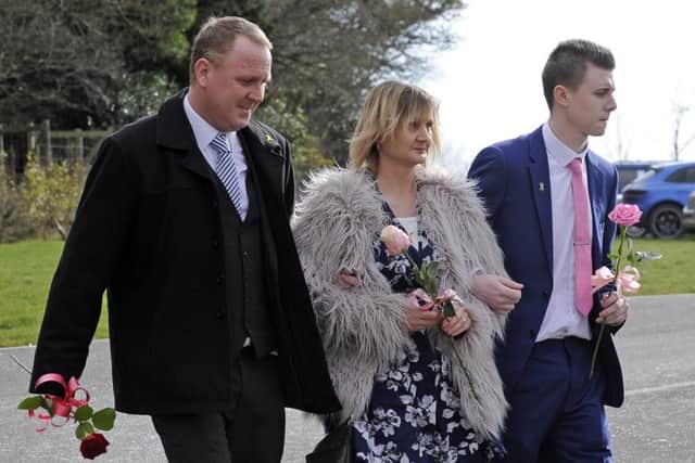 Katie's parents Michelle and Jason and her brother Harry carry roses at the funeral