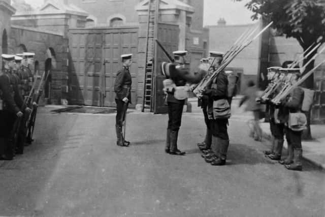 With long gunnery gaiters and bayonets fixed to their rifles, we see Royal Marines changing guard  just inside Eastney Barracks main gate. Picture: Robert James Collection