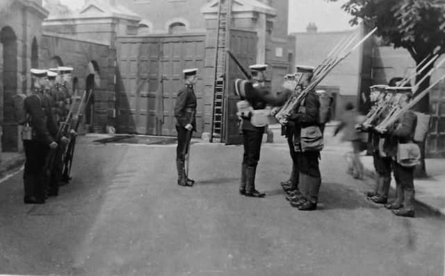 With long gunnery gaiters and bayonets fixed to their rifles, we see Royal Marines changing guard  just inside Eastney Barracks main gate. Picture: Robert James Collection