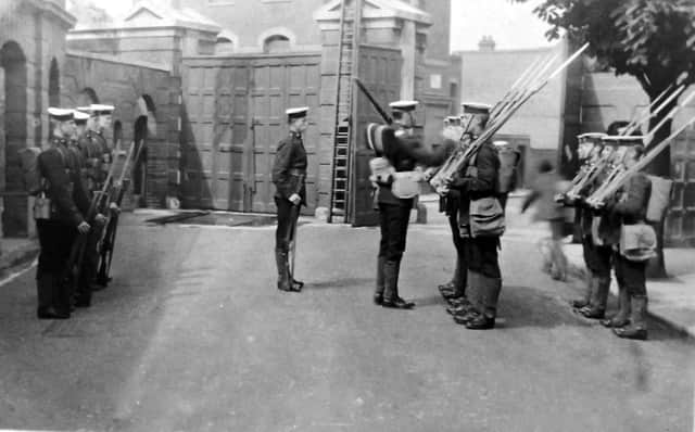 With long gunnery gaiters and sword bayonets fixed to their rifles, we see marines changing guard just inside Eastney Barracks main gate. Robert James Collection