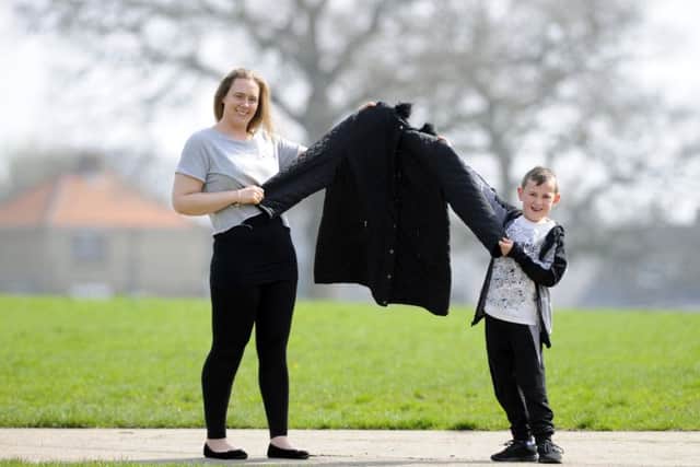 Chantelle Cowdrey with son Rhys, holding up the size 24 coat she once had to wear - before her 9st weight-loss
Picture by: Malcolm Wells (180411-0805)