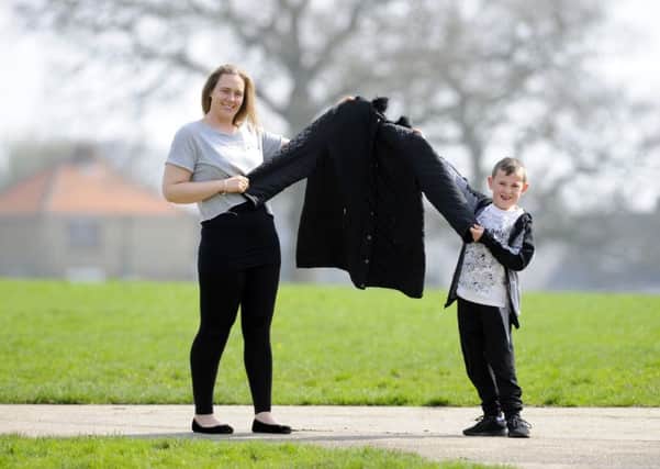Chantelle Cowdrey with son Rhys, holding up the size 24 coat she once had to wear - before her 9st weight-loss  
Picture by:  Malcolm Wells (180411-0805)