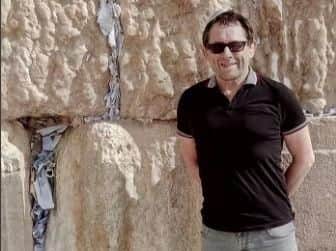 Chris stands alongside wondrous Western or Wailing Wall, where Divine Presence dictates written wishes come true after insertion in cracks.