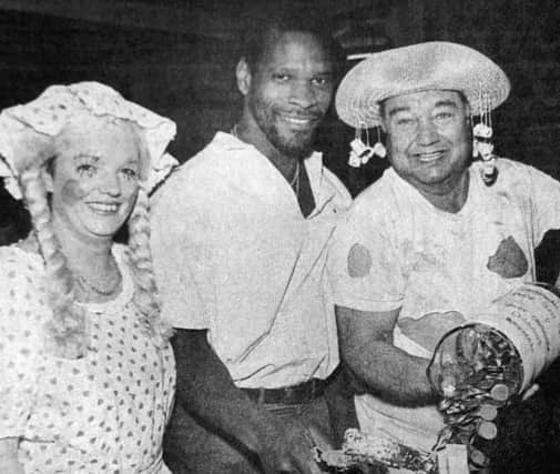 Noel Blake and two people in fancy dress. Please caption: Noel Blake smashes the charity collecting bottle at The Sportsman's Rest pub, Copnor Road, as landlord BobMason, right, and his wife Paula, both in fancy dress, wait to count the money which went to aid the News Scanner Appeal and Great Ormond Street Hospital