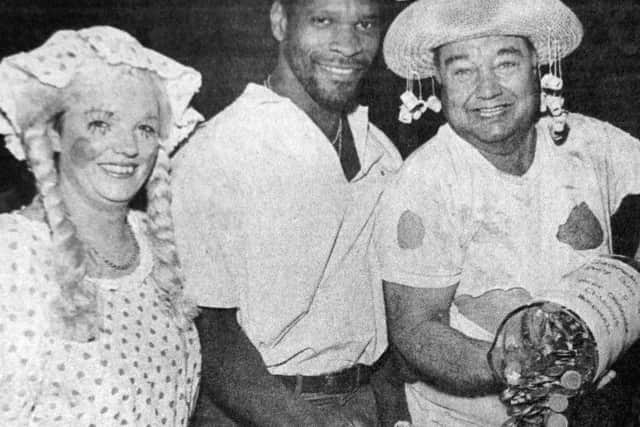 Noel Blake and two people in fancy dress. Please caption: Noel Blake smashes the charity collecting bottle at The Sportsman's Rest pub, Copnor Road, as landlord BobMason, right, and his wife Paula, both in fancy dress, wait to count the money which went to aid the News Scanner Appeal and Great Ormond Street Hospital
