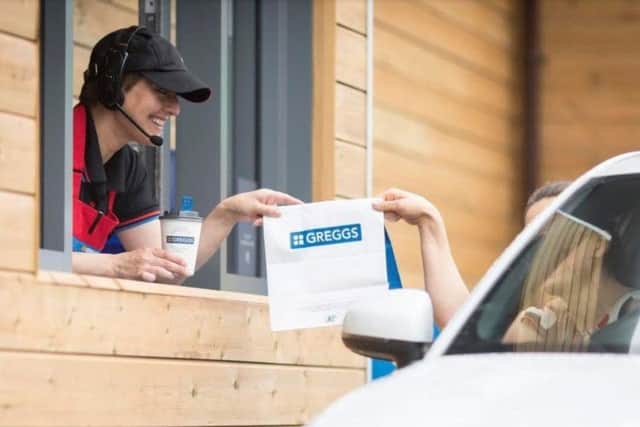 A customer receives an order at a drive-through Greggs outlet