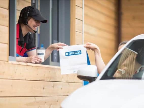 A customer receives an order at a drive-through Greggs outlet
