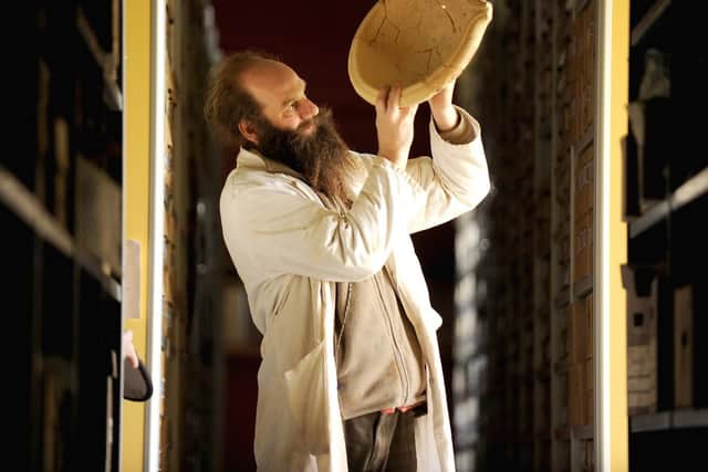 Dr Rob Symmons holding up a mortarium in the Stores of the Collections Discovery Centre at Fishbourne Roman Palace.