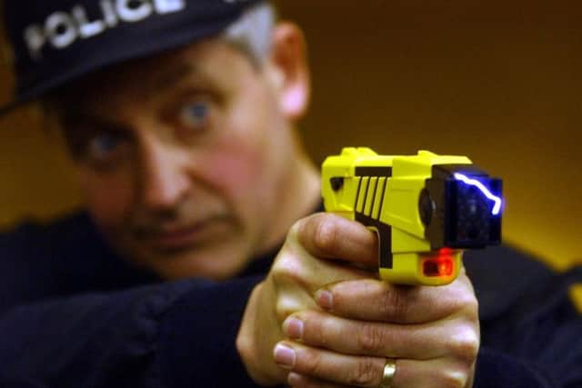 A police officer demonstrates the firing of taser gun, which delivers an electric shock to stun a suspect